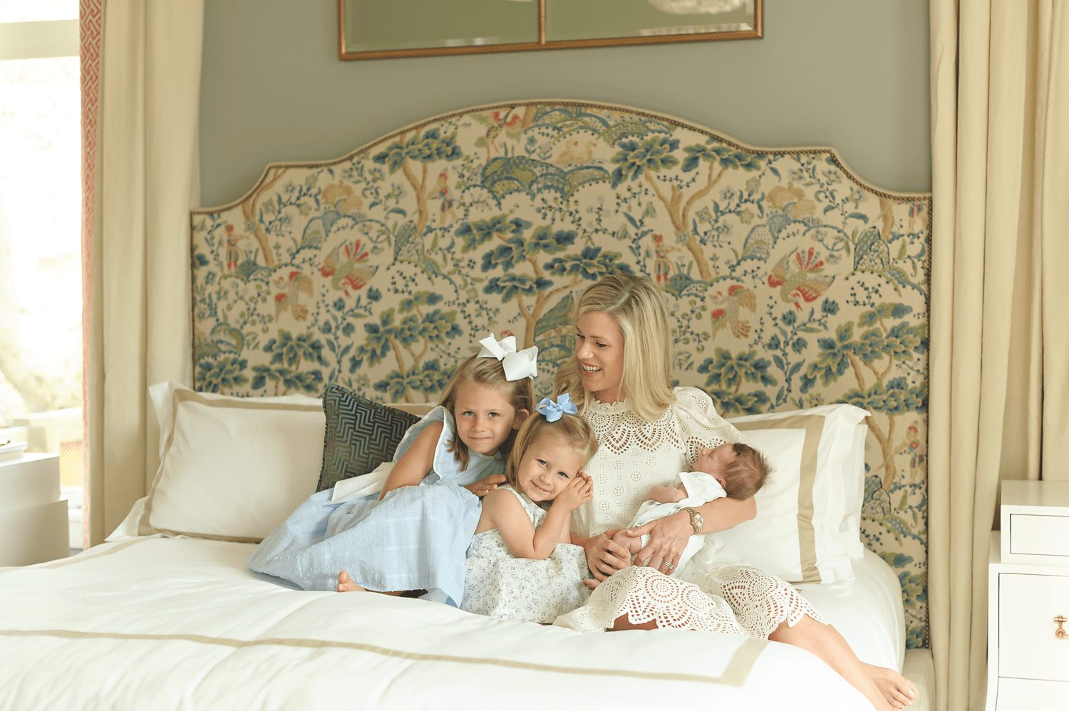 Mom with newborn and daughters on bed