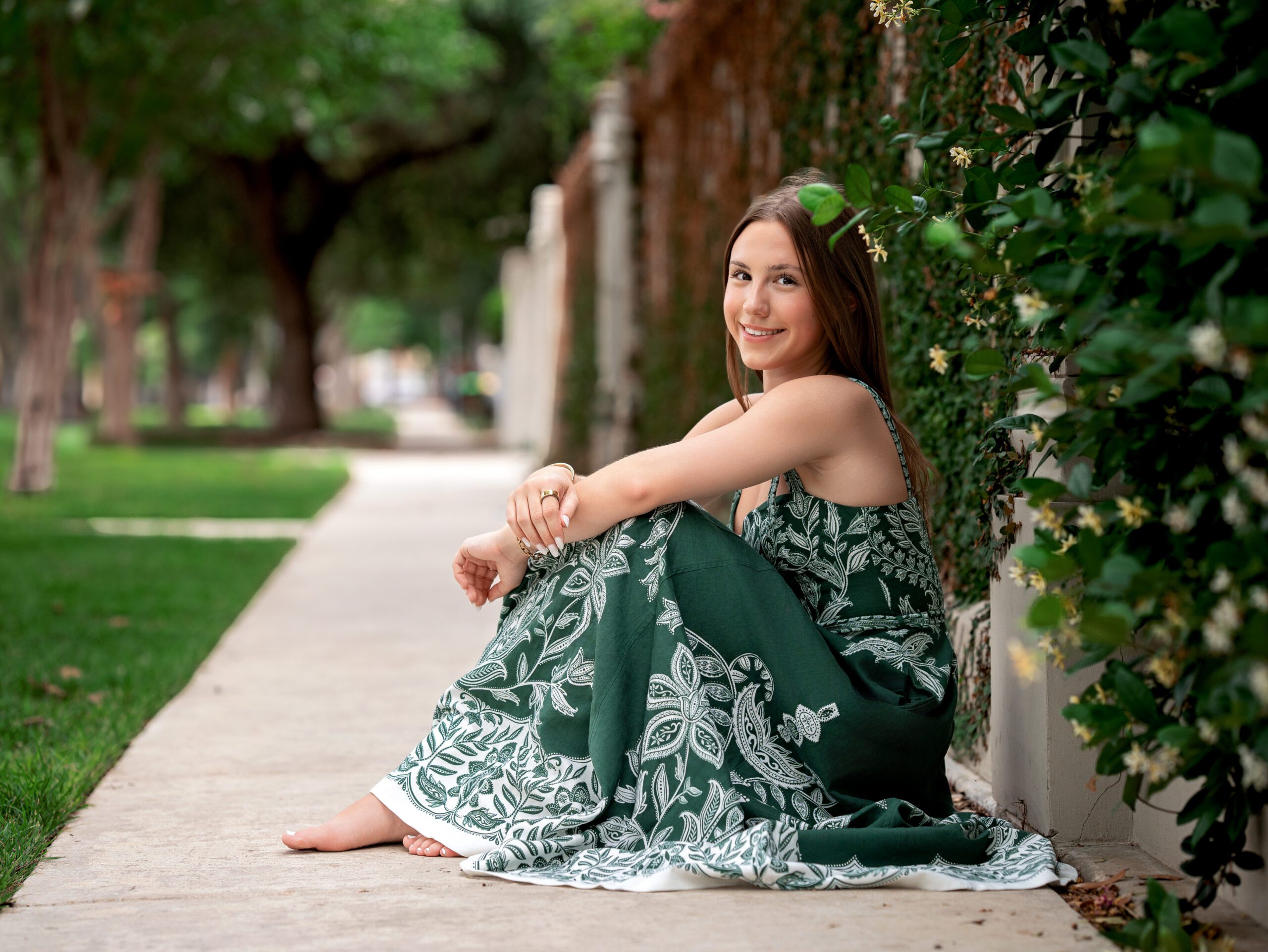 A full-length shot of a senior in a flowy, unexpected dress against a natural outdoor backdrop